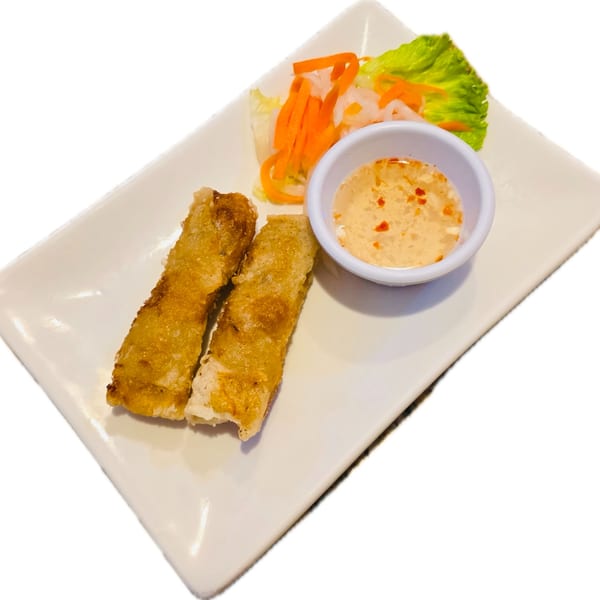 Two crispy Vietnamese spring rolls with a side of dipping sauce and pickled vegetables.